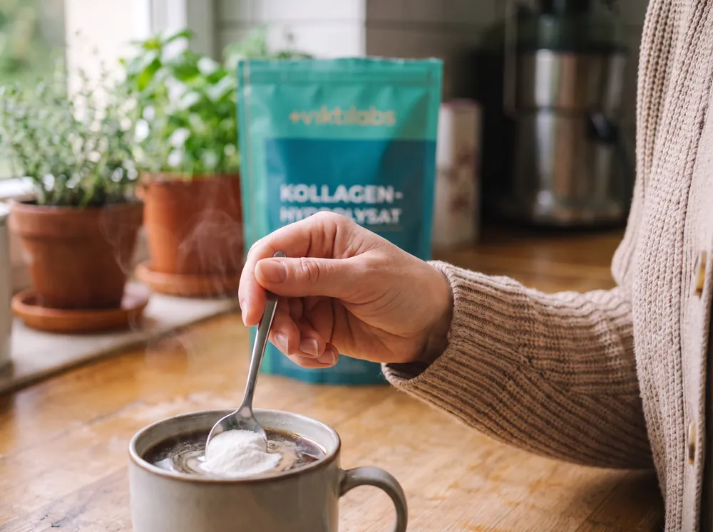 Hand rührt einen Löffel Pulver in eine Kaffeetasse